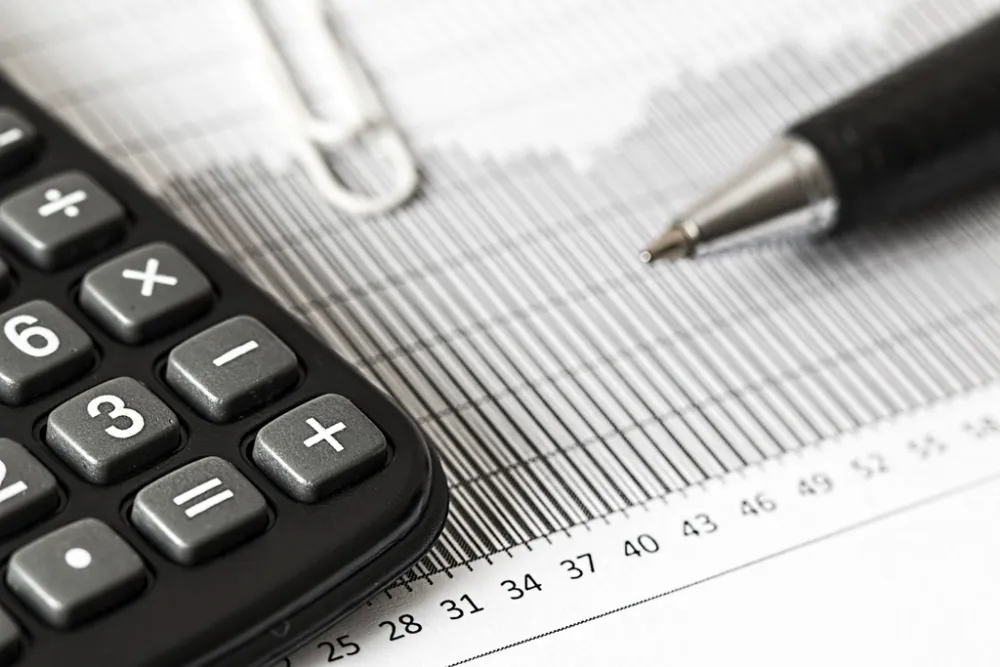 A calculator and pen on a numbers chart — plan your emergency fund and protection before investing