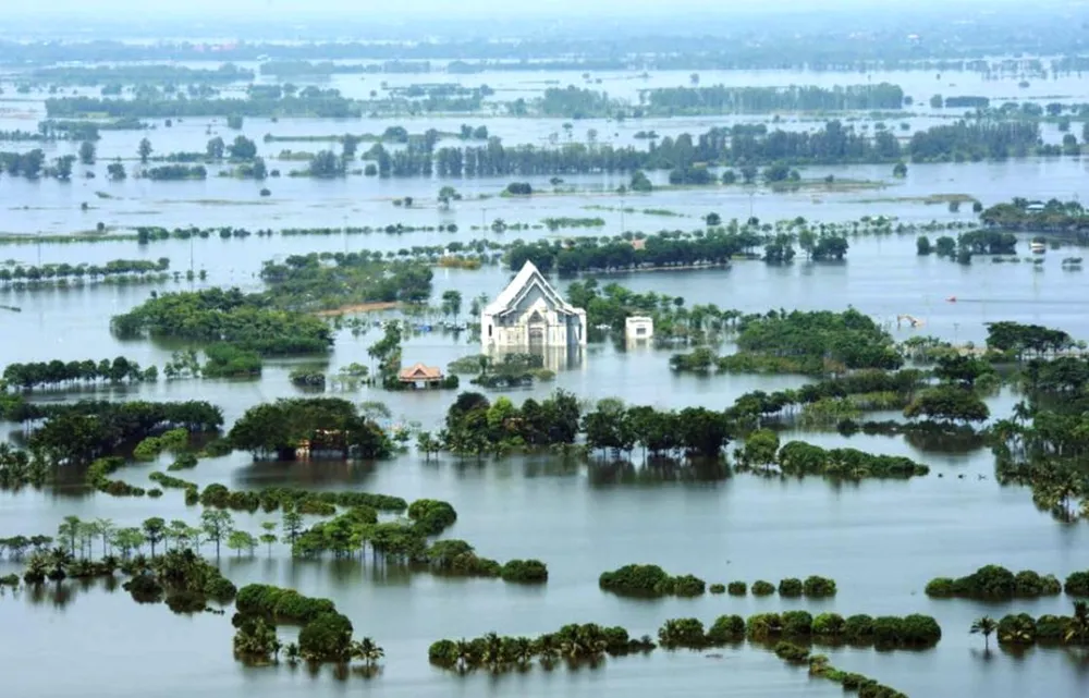 Aerial view of a house and temple submerged in floodwater in Central Thailand in 2011, with only the roof and treetops visible above the water