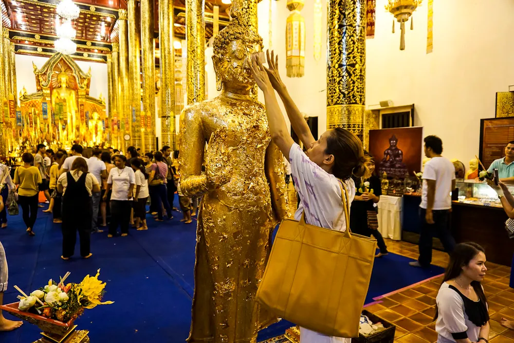 ผู้คนปิดทองพระพุทธรูปที่วัดในเชียงใหม่ (ภาพประกอบ)