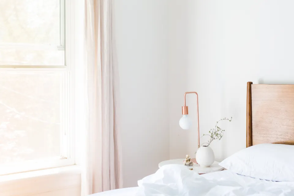 A bright, airy bedroom with a bed, white linens and natural light