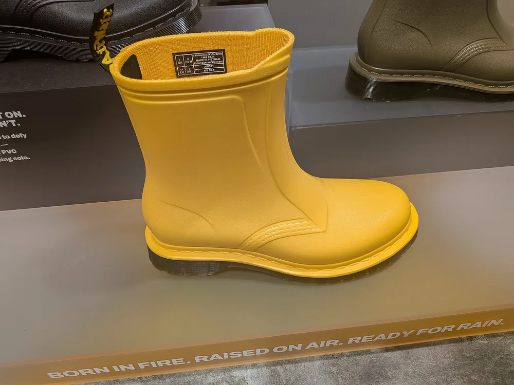 A bright yellow rubber rain boot on display, an example of the knee-high waterproof shape