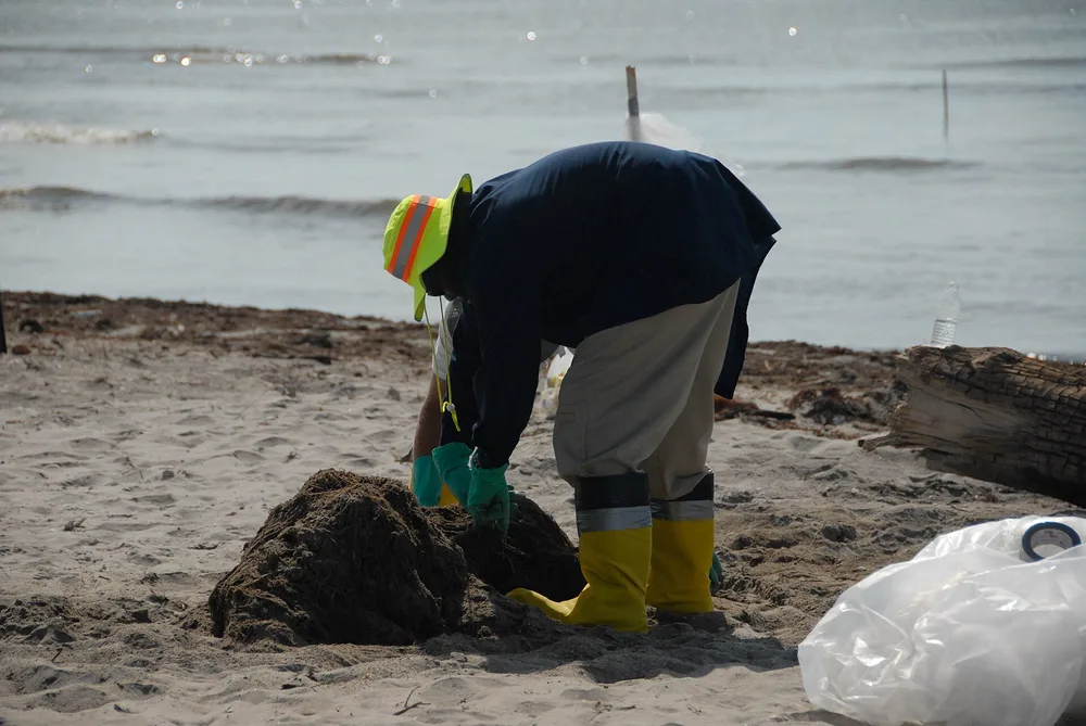 Yellow rubber boots with a reflective strip, worn during a beach cleanup