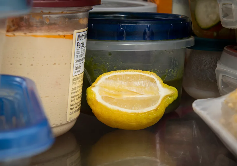 Food containers and a fresh lemon stored on a refrigerator shelf — a fridge with good temperature stability keeps food fresh 2–3 days longer