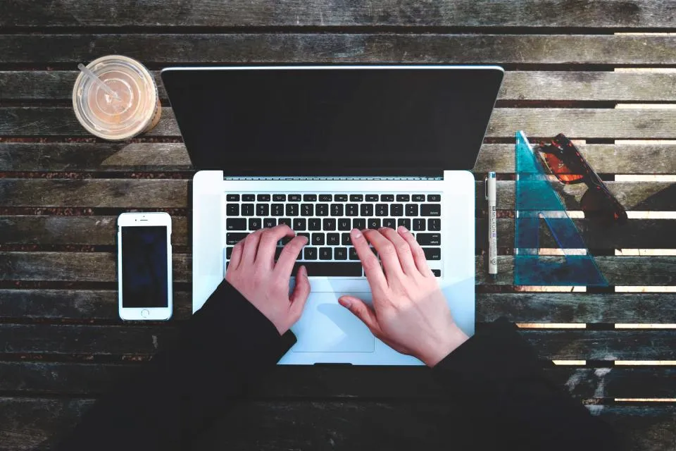 Student typing on a laptop at a café — top-down view