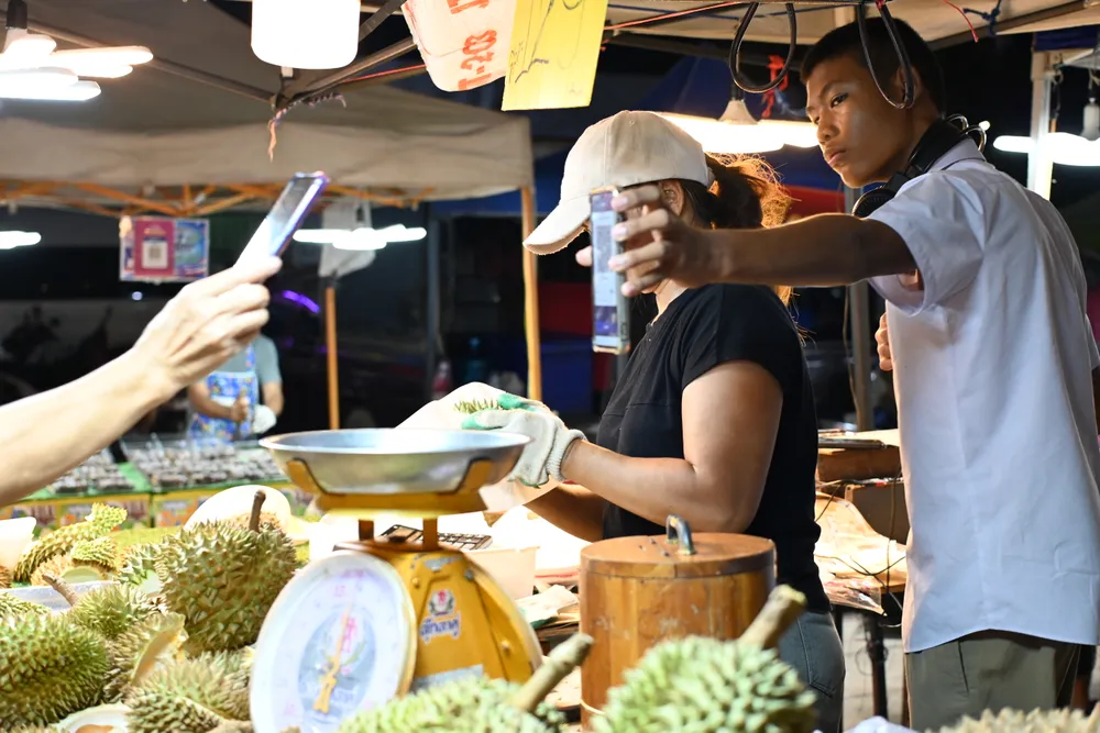A person paying with a phone at a Thai market stall