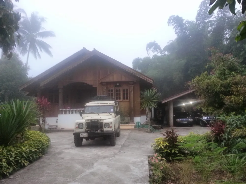 A wooden house and a 4WD in morning mist, illustrating the Umphang atmosphere
