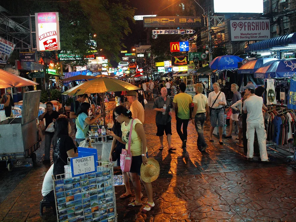 Khao San Road in Bangkok at night, crowded with tourists under bright neon signs