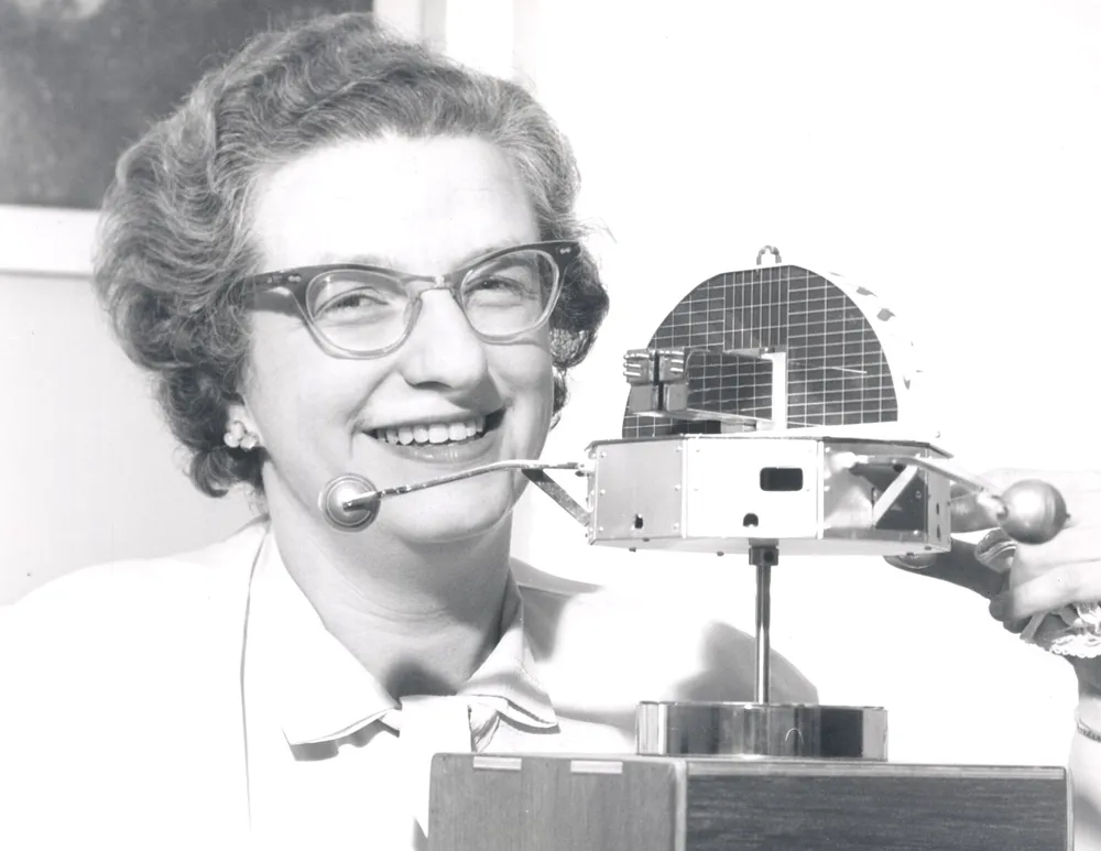 ภาพถ่ายของ Nancy Grace Roman ถือแบบจำลองดาวเทียมในยุคที่เธอเป็นหัวหน้านักดาราศาสตร์ของ NASA