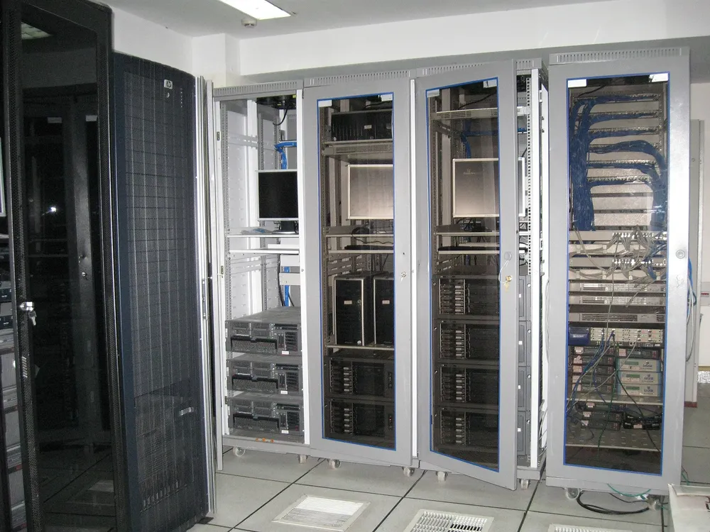 Rows of server racks in a data center lit with blue lights