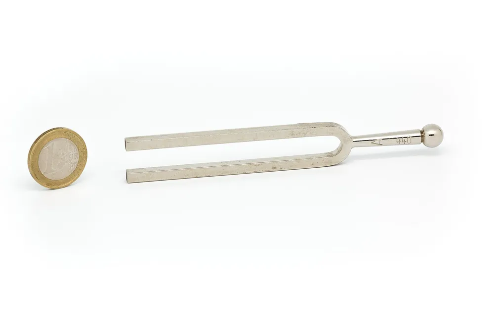 A real tuning fork next to a 1-euro coin, illustrating the same principle as the microscopic quantum resonator used in the experiment