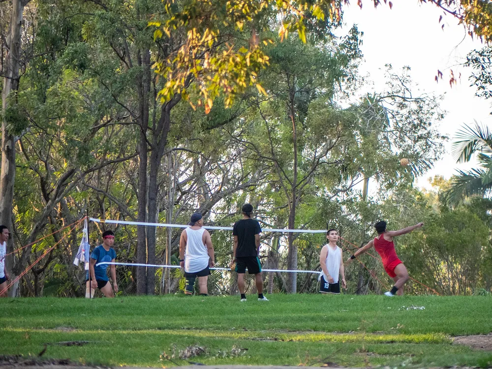 Outdoor sepak takraw match, a player leaping to spike over the net