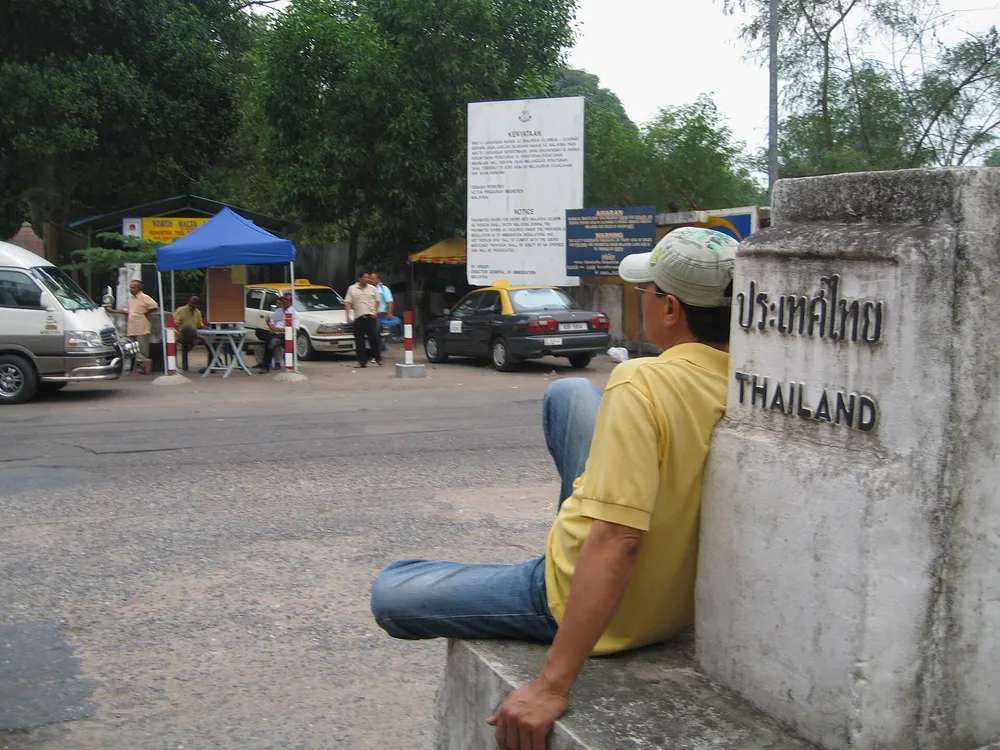 The "ประเทศไทย / THAILAND" boundary marker at the Bukit Kayu Hitam crossing — Wikimedia Commons (PD)
