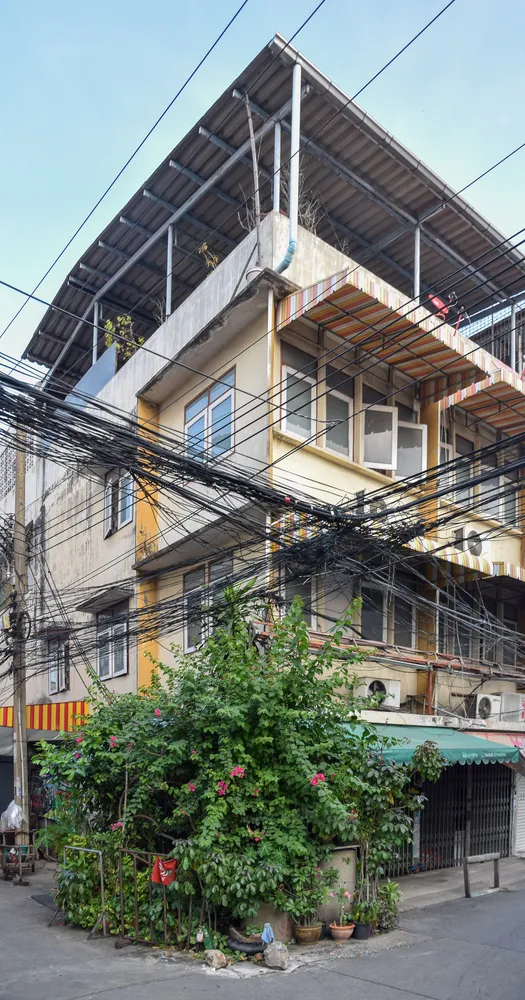 Overhead power lines crossing a residential building in an older Bangkok neighborhood